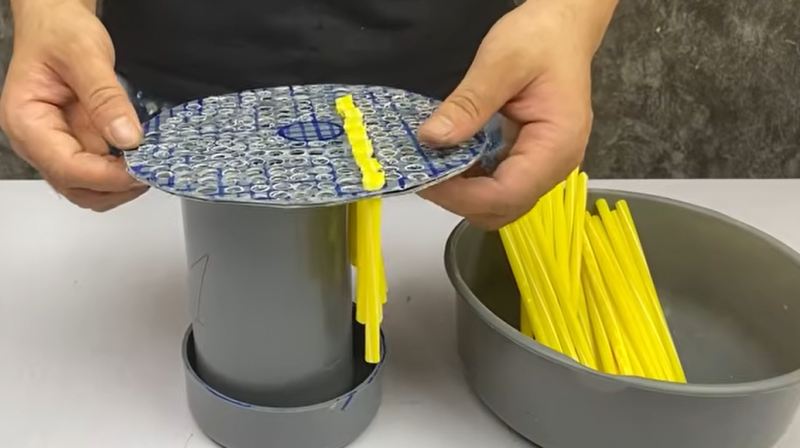 قرار دادن نی های رنگی در سوراخ های صفحه PVC برای ساخت برس گردگیر